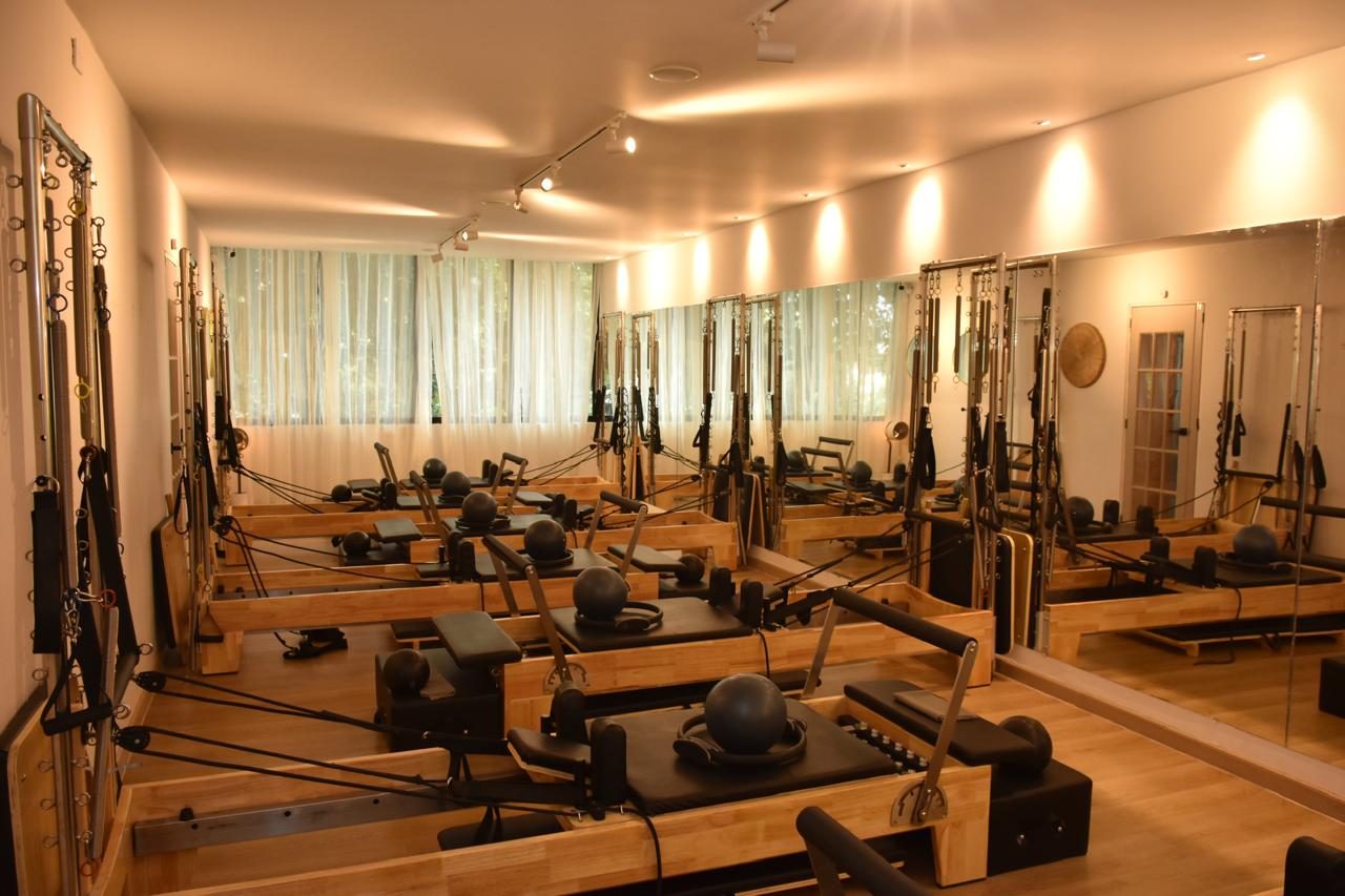Reformers de madera alineados en la sala de pilates